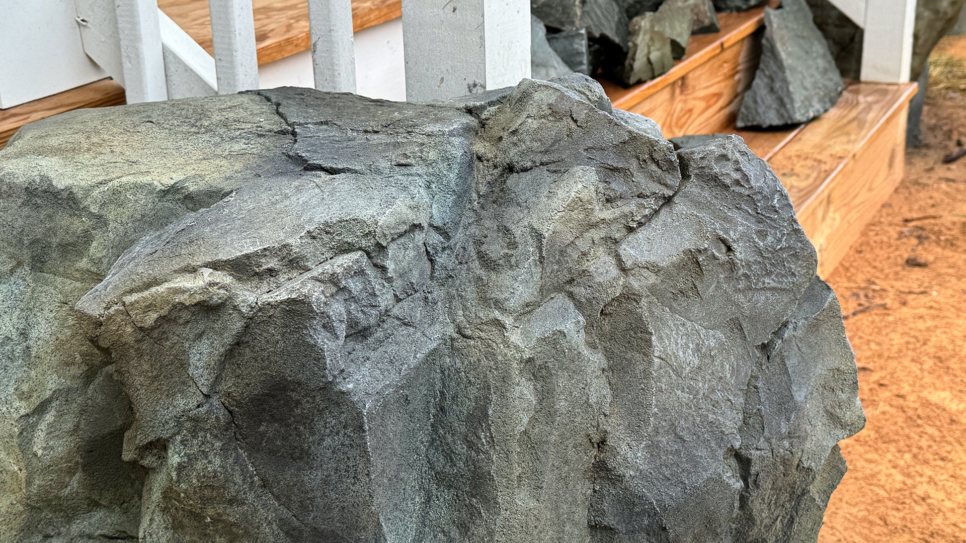 close-up photo of finished blue-toned simulated realistic rock in front of house.